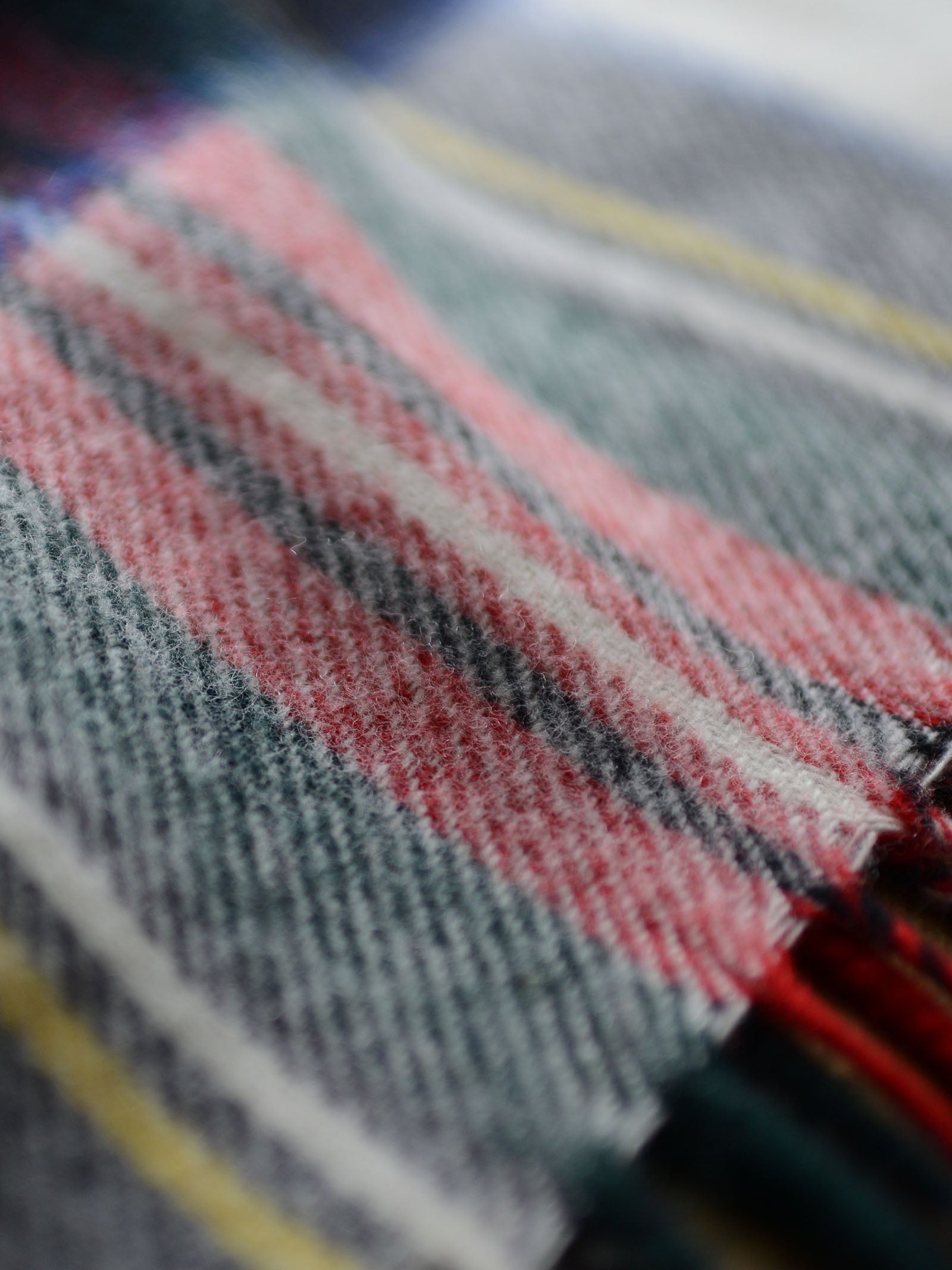 Close-up of the Lambswool Tartan Blanket by Campbell's of Beauly, showing its soft woven texture and classic red, white, gray, green, and yellow plaid—reflecting traditional UK craftsmanship.