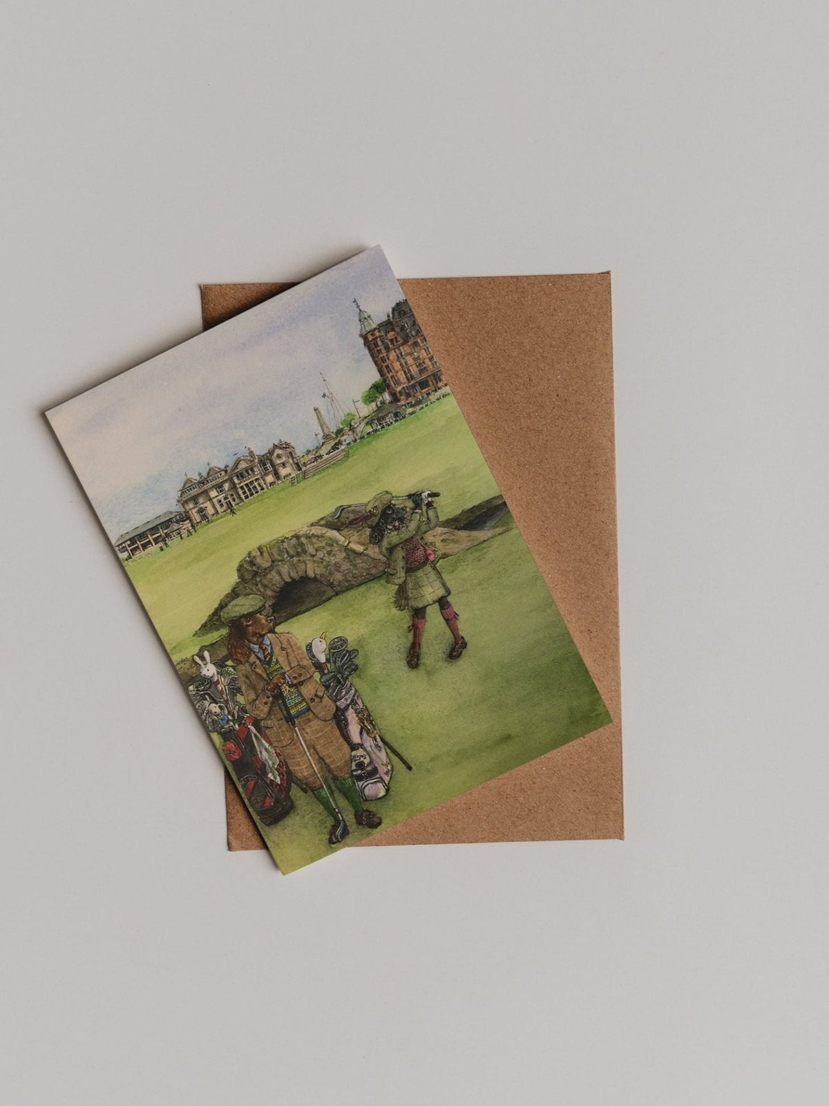 The St Andrews Swilken Bridge Greeting Card by Campbell’s of Beauly is shown atop a brown envelope against a plain white background.