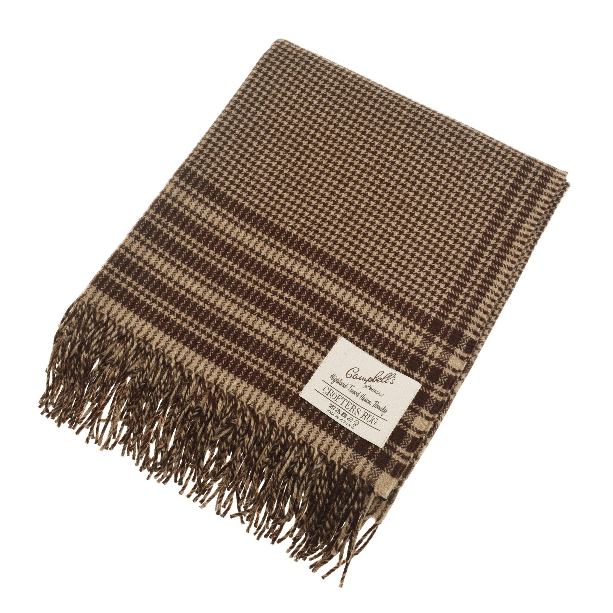 A folded Crofters Blanket from Campbell's of Beauly features a brown and beige houndstooth pattern, fringed edges, and a sewn label in the corner for brand and care details, lending a classic country style.