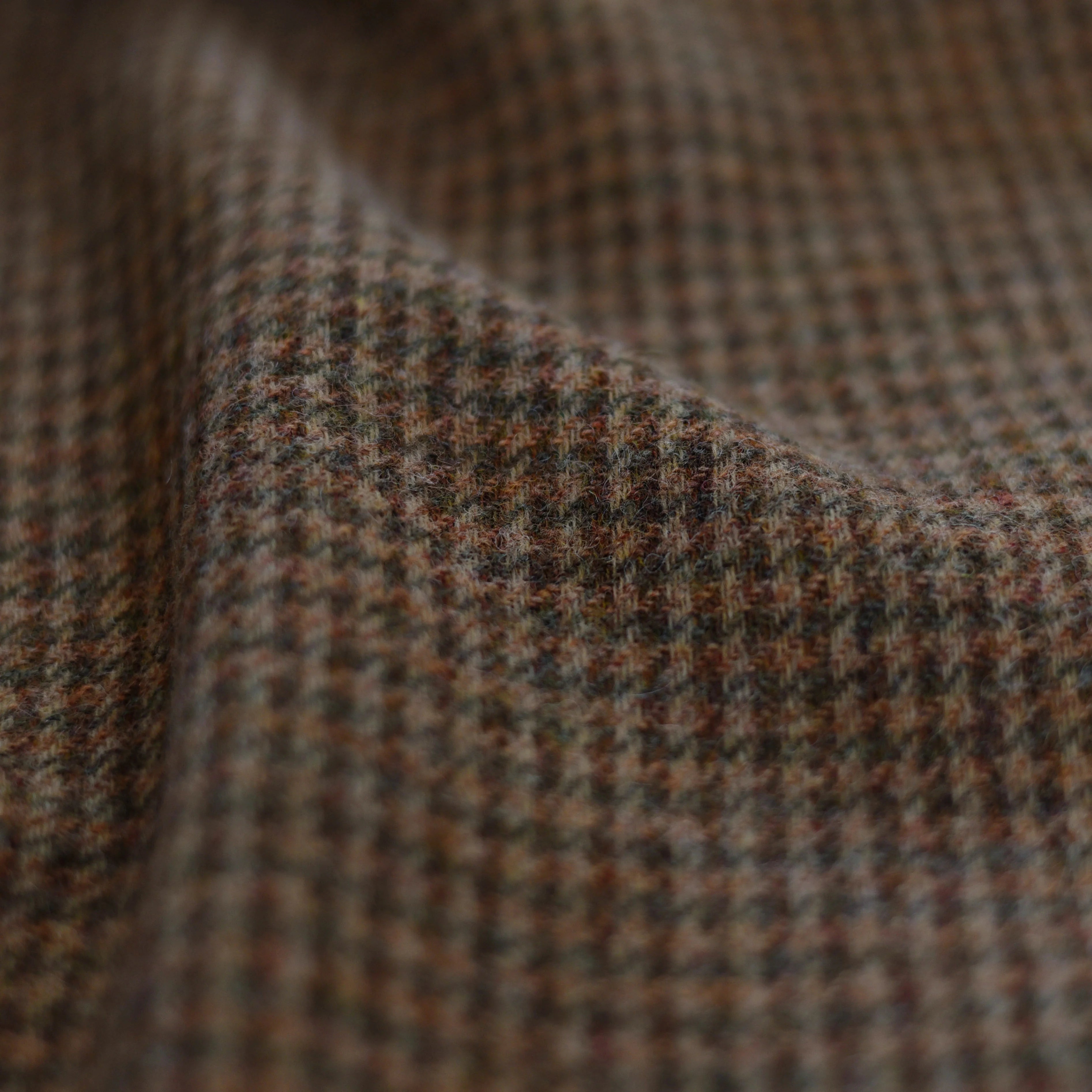 Close-up of House Tweed 11055 by Campbell's of Beauly—a brown and green Shetland tweed in a small houndstooth pattern, highlighting its soft texture and classic jacketing weight, perfect for a 100% wool jacket.