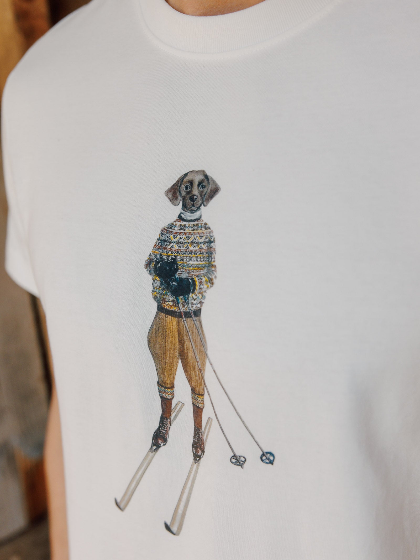 The Le Ski Labrador T-Shirt by Campbell's of Beauly is a white cotton tee featuring a graphic of a skiing labrador—perfect for winter sports lovers.