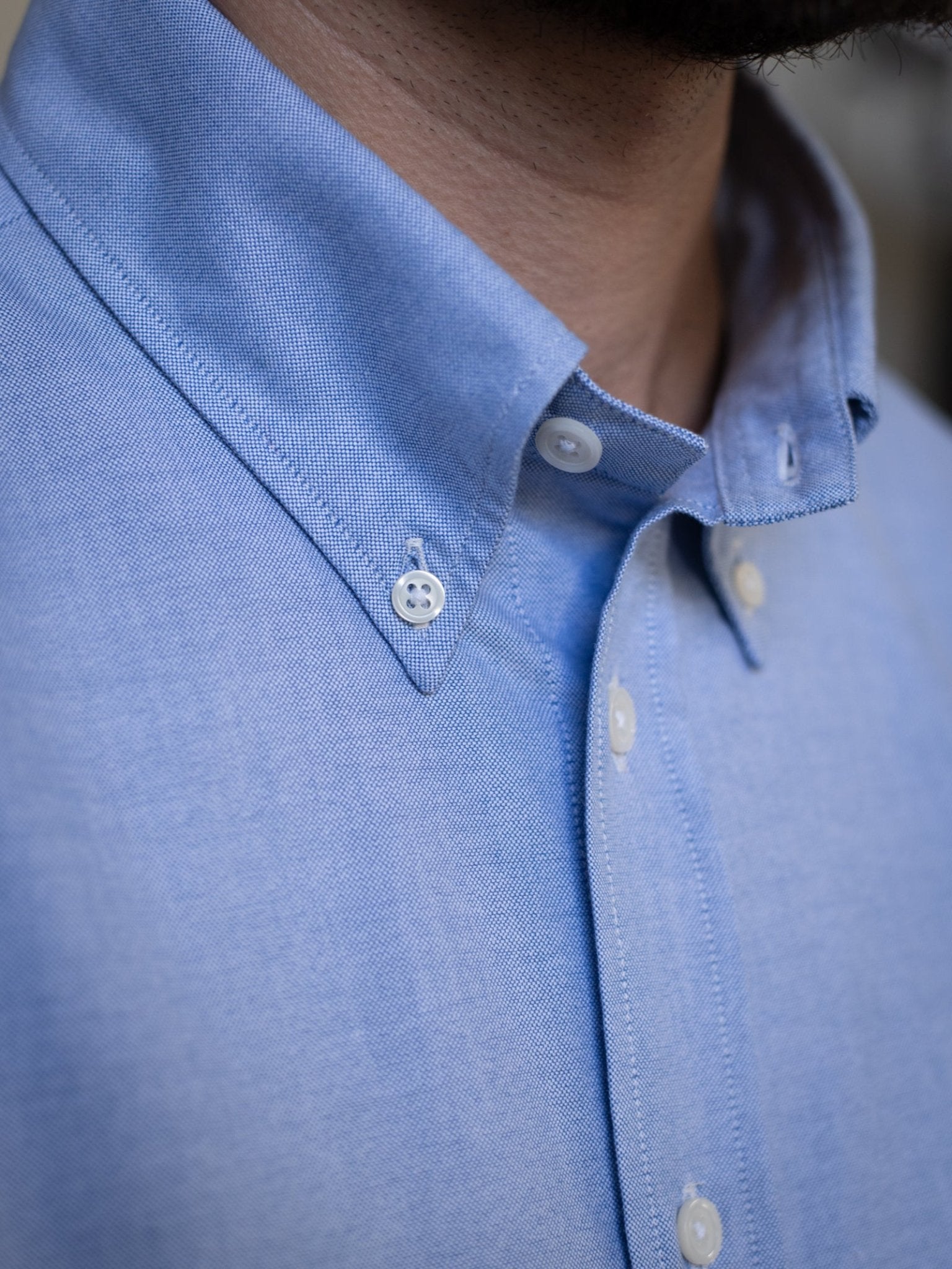 Close-up of a person wearing the Campbell's of Beauly Oxford Button Down Shirt in light blue, highlighting its crisp collar and white buttons. Only part of the neck and chin are visible; the face is mostly out of frame.