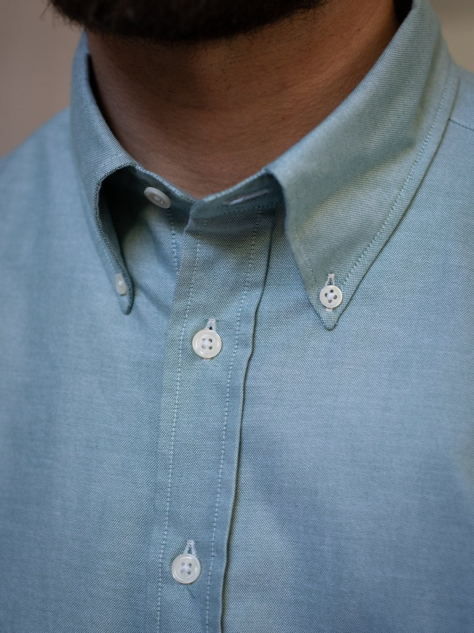 Close-up of a person wearing Campbell's of Beauly Oxford Button Down Shirt in light blue cotton with white buttons and a fastened collar—an ideal choice for stylish summer wear.