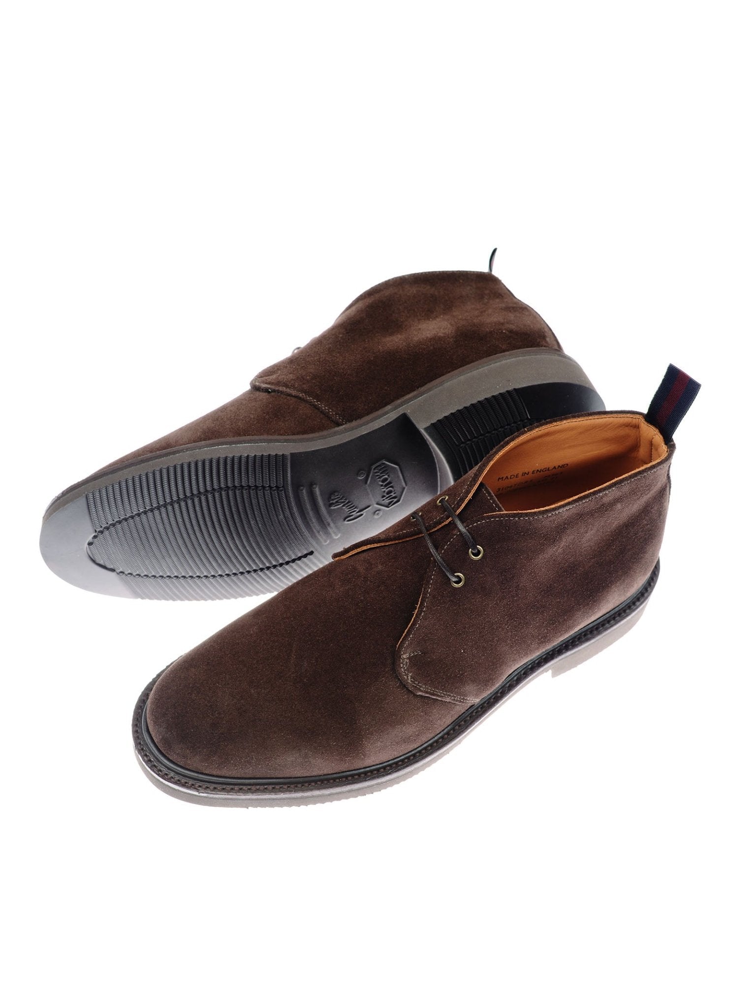 A pair of Campbell's of Beauly Lomond Boots in brown suede with dark soles—one boot upright and the other on its side to display both the top view and the ridged sole—featuring tan leather lining and a striped pull tab.