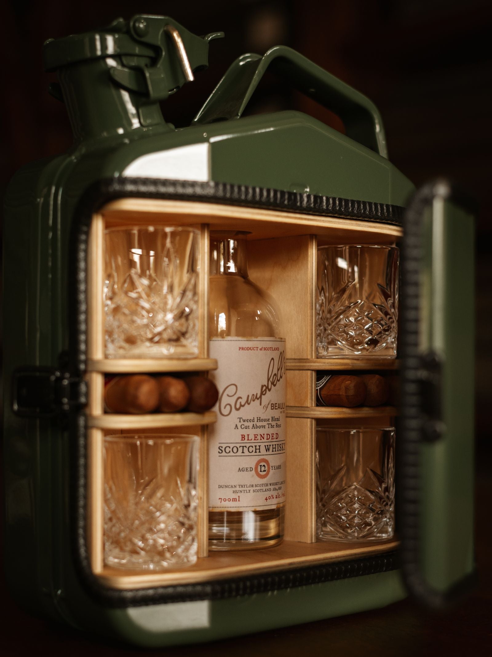 The Mini Connoisseur Upcycled Mini Bar by Campbell's of Beauly is made from a green upcycled Jerry can, opening to reveal a bottle of blended scotch whisky, four crystal glasses, and compartments with wooden spheres.