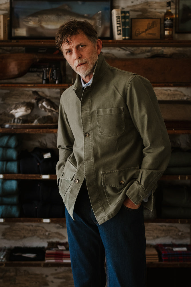A man wearing an olive green cotton moleskin Nevis Jacket by Campbell’s of Beauly featuring chest and hip pockets.