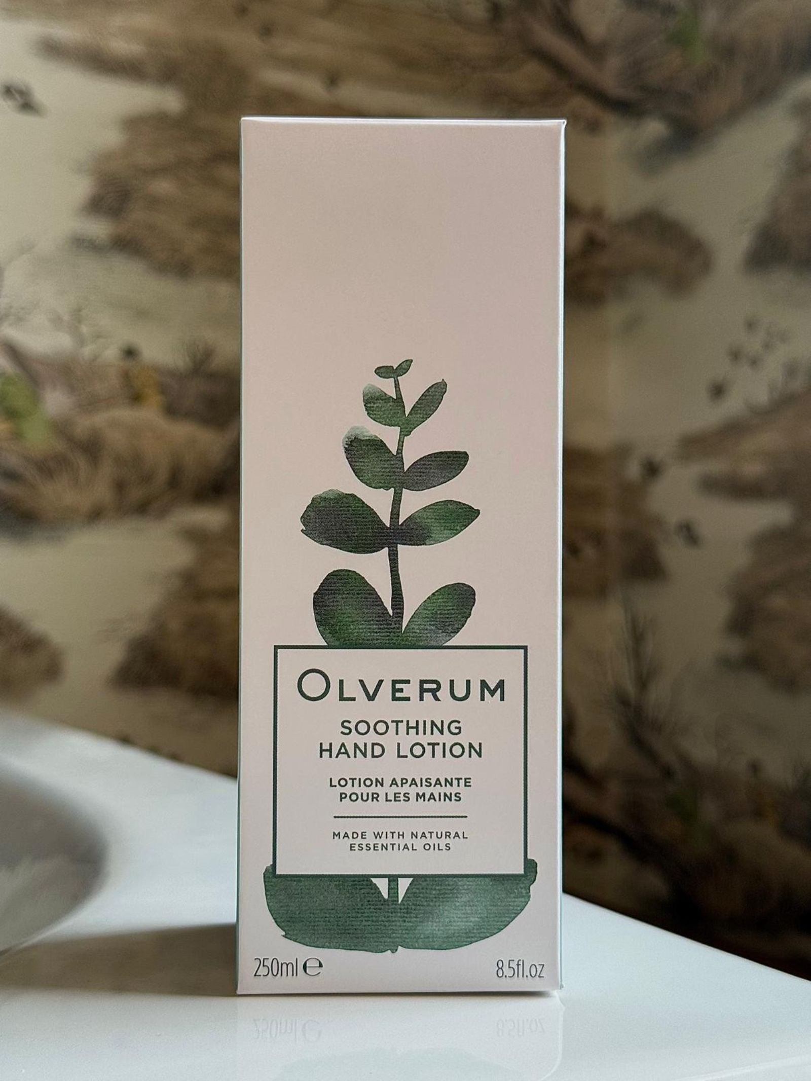 A 250ml box of OLVERUM Soothing Hand Lotion featuring a minimalist design with a green plant illustration. This vegan lotion is made with natural essential oils.