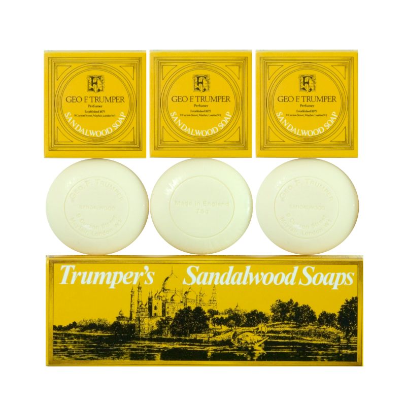 Three oval white soaps are shown with yellow and gold boxes labeled "Geo. F. Trumper Sandalwood Hand Soaps, Set of 3," above a larger box featuring an illustrated landscape and marked as "Trumper’s triple-milled Sandalwood Soaps.