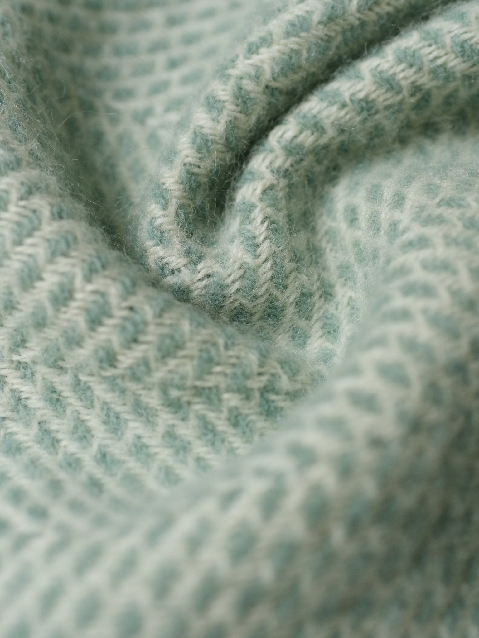Close-up of the Stipled Twill Blanket by Campbell's of Beauly, showing soft light blue knitted fabric with a textured pattern and gentle folds that highlight its detailed stitches and cozy, breathable appearance.