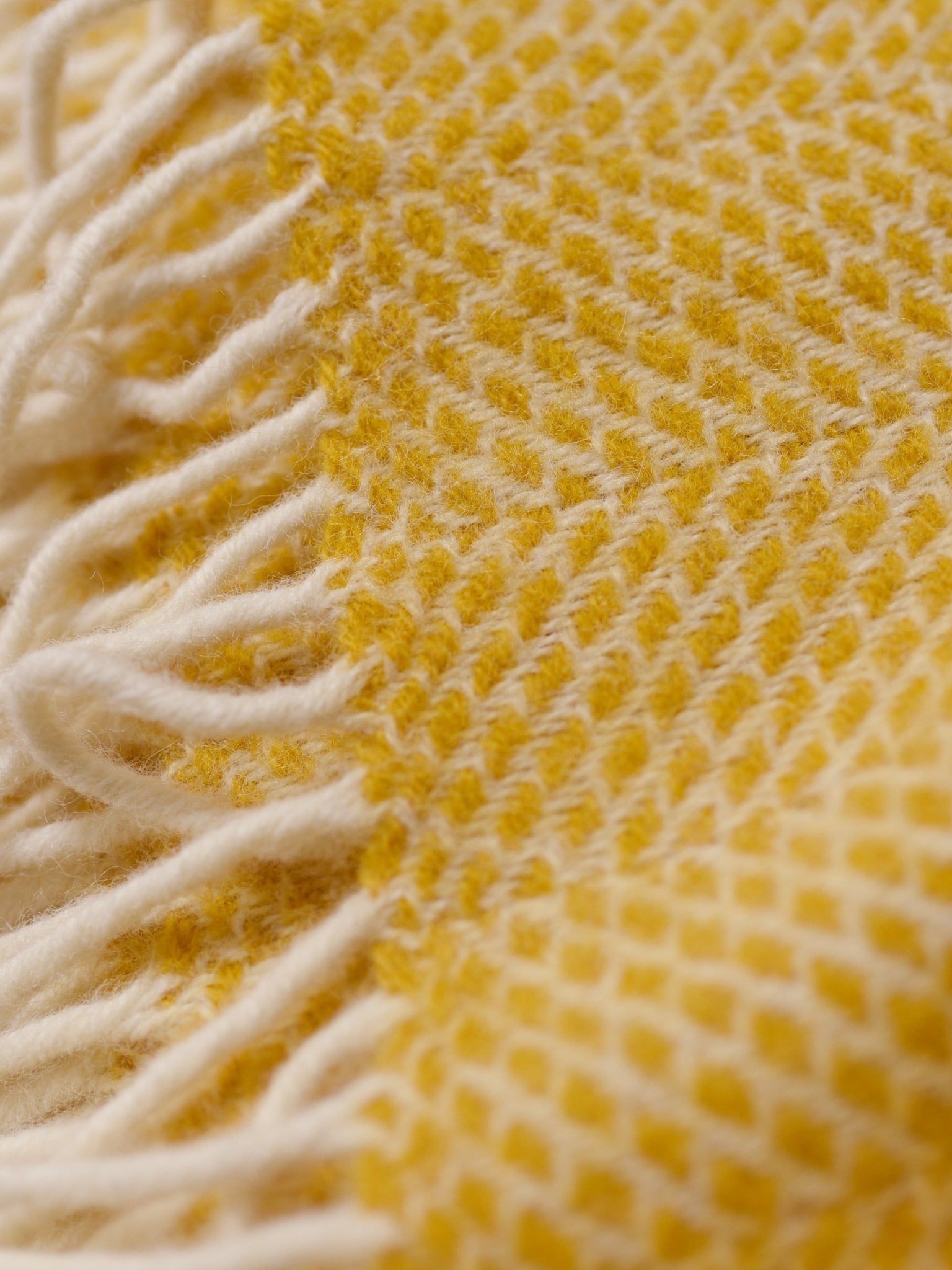 Close-up of the Stipled Twill Blanket by Campbell's of Beauly, featuring a yellow and white diamond pattern, fringed edges, and a breathable weave for cozy texture and airy comfort.