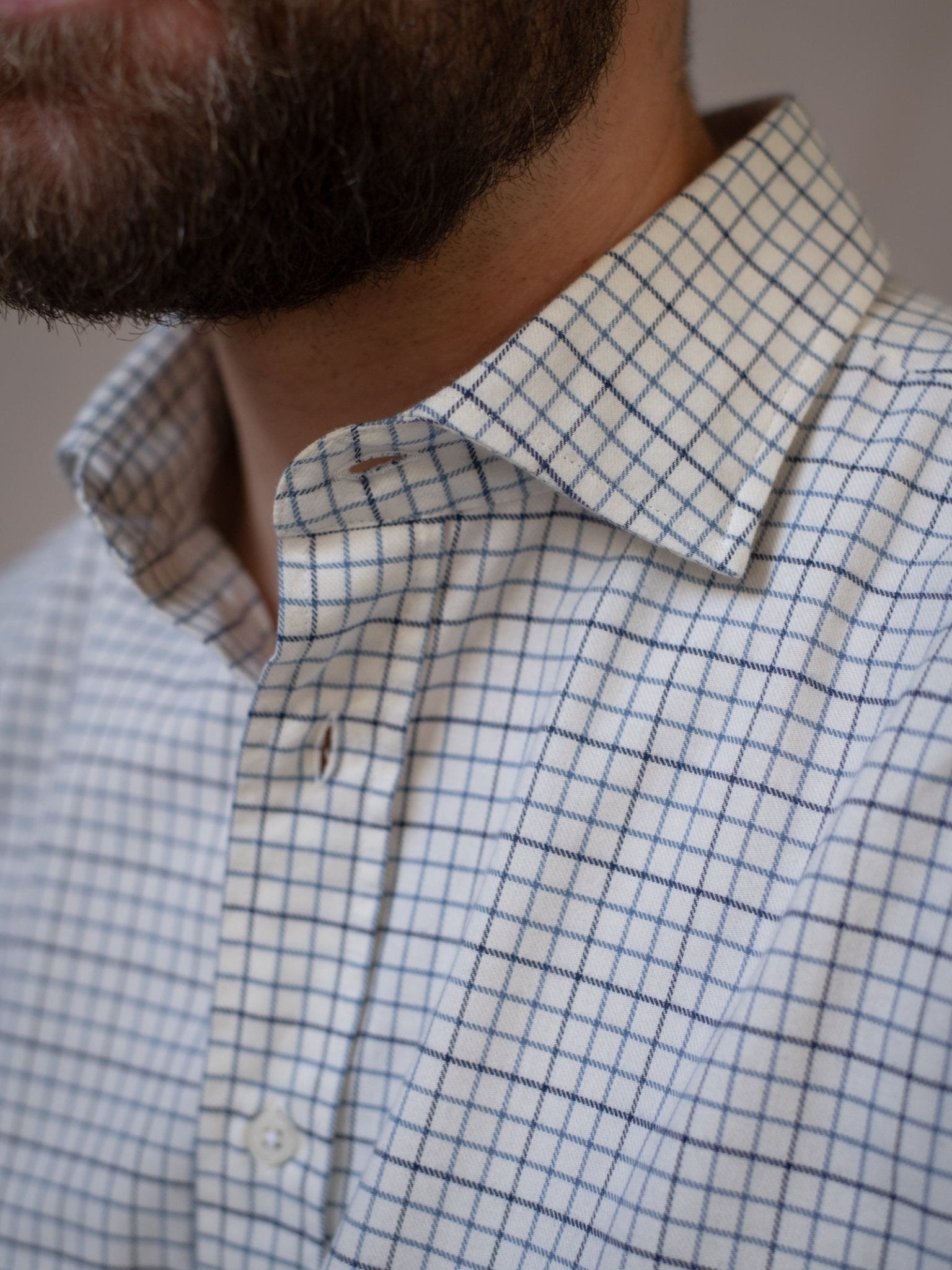 Close-up of a man with a beard wearing the Campbell's of Beauly Windowpane Shirt, featuring a white base with a blue grid pattern and a button-down collar.